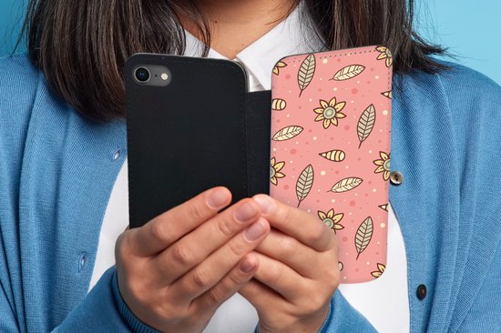 Vrouw houdt telefoonhoesje met roze bloemen- en bladerenpatroon vast. Zwarte binnenkant.