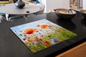 Een inductiebeschermer met klaprozen en korenbloemen op een zwart aanrecht.