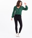 Model met zwarte broek met strikceintuur en groen hartjesblouse.