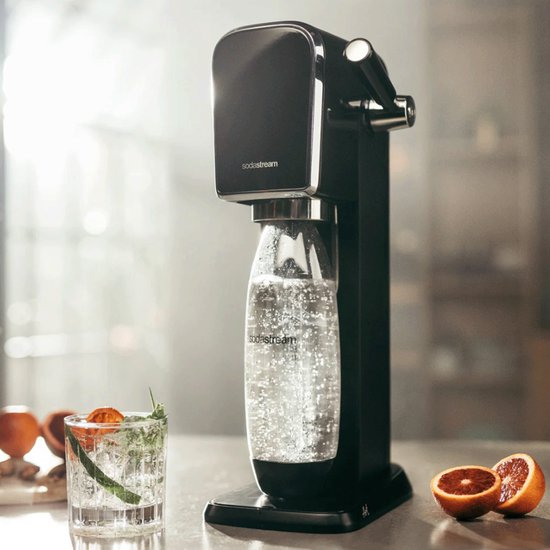 Zwart SodaStream ART bruiswatertoestel met een fles bruiswater, naast een glas en sinaasappelpartjes.