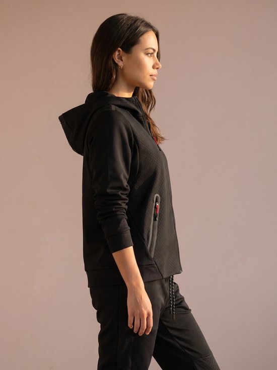 Zijaanzicht van een model van achteren, met zwarte hoodie met rits, witte top en zwarte broek. De hoodie heeft een ruitpatroon.