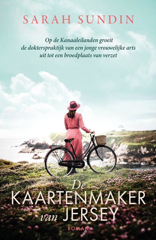 Vrouw in roze jurk en hoed staat met fiets en mandje bij rotsachtige kust. "De kaartenmaker van Jersey."