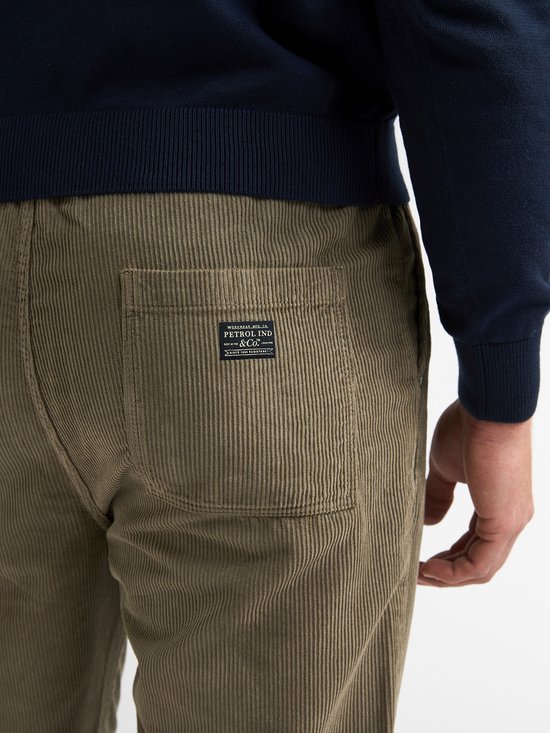 Detail van de achterzak op een olijfgroene corduroy broek met Petrol Ind. & Co. label.