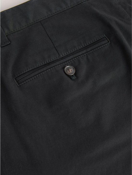 Detailopname van een achterzak met knoopsluiting op een zwarte chino.
