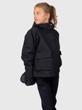 Meisje in zwarte ski-jas met capuchon, ski-broek en ski-handschoenen, kijkt weg.