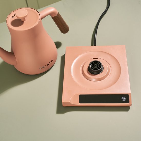 Roze waterkoker met houten handvat en bijpassende roze basis met digitale display.