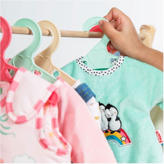 Meisje pakt turquoise poppen romper met pinguïns en regenboog op de kleerhanger.