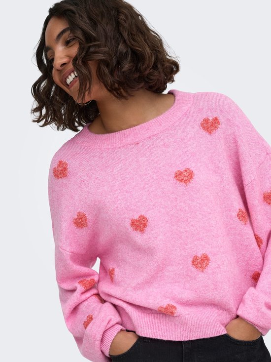 Roze trui met all-over rode hartjesprint, model met opgestoken armen en kraag.