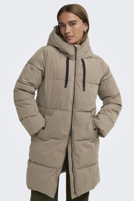 Vrouw in lang, beige pufferjack met hoge kraag en capuchon, zwarte rits en trekkoorden.