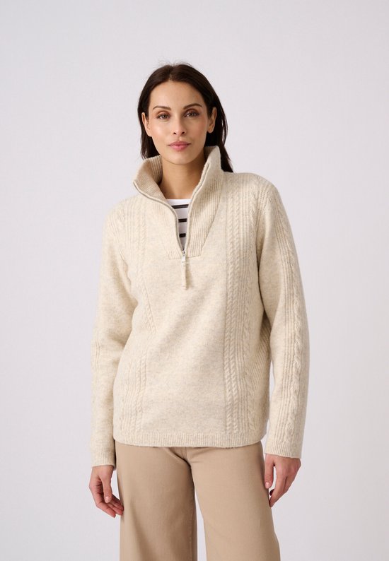 Vrouw met gebreide beige trui met kabelpatroon en halve rits.