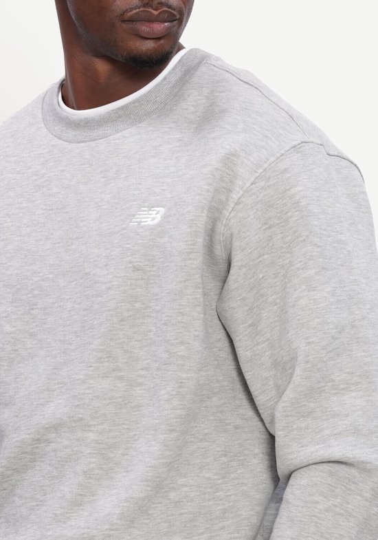 Grijze New Balance sweater met wit logo op de borst.