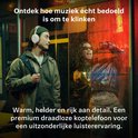 Jongeman met witte koptelefoon, staand in een straat met neonlicht. Ontdek hoe muziek écht bedoeld is om te klinken.