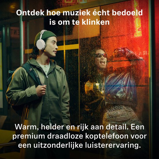Jongeman met witte koptelefoon, staand in een straat met neonlicht. Ontdek hoe muziek écht bedoeld is om te klinken.