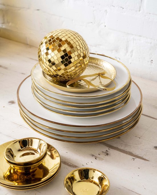 Stapel witte borden met gouden randen, bekroond met een gouden discobol. Kleine gouden schaaltjes ernaast.