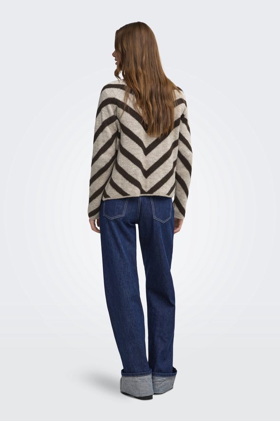 Achterkant van een lichtbruine trui met donkerbruine chevronprint, gedragen door een model met een witte blouse en jeans.