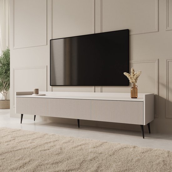 Wit tv-meubel met verticale ribbelpatroon en zwarte pootjes. Gedecoreerd met vaas en mok.