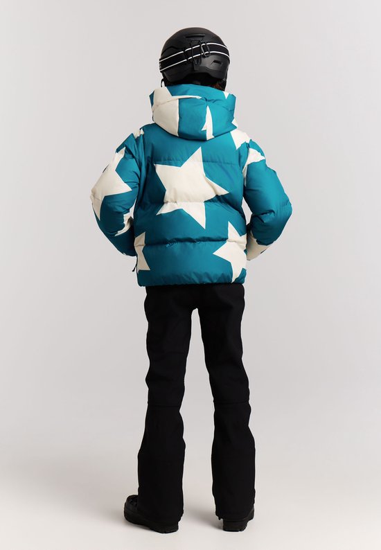 Meisje in blauwe winterjas met sterrenprint, zwarte skibroek en skihelm, van achteren gezien.