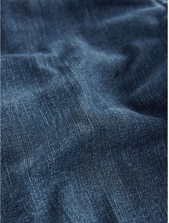 Textuur van donkerblauwe denim stof met subtiele vouwen.