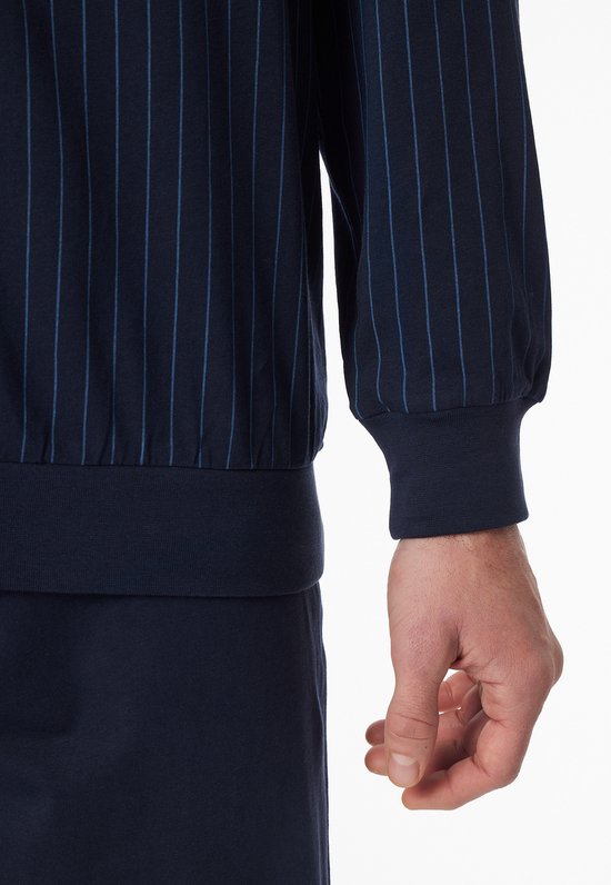 Close-up van de polsband van een donkerblauwe pyjamatop met verticale strepen.