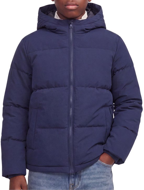 Jongen draagt een donkerblauwe pufferjas met de hand in zijn zak.