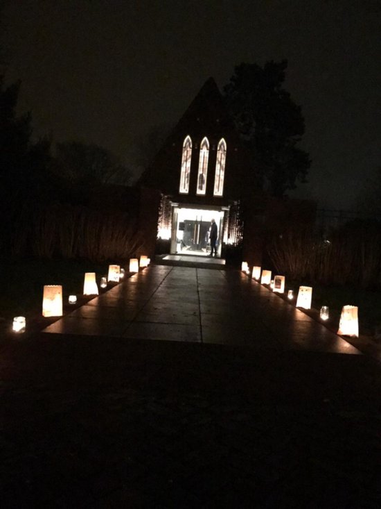Ingang van een gebouw 's nachts, verlicht door papieren lantaarns op het pad.