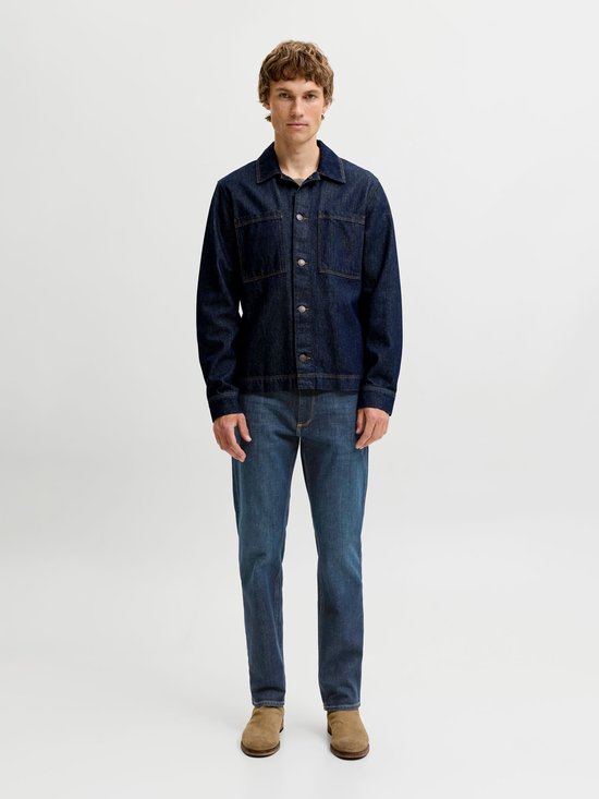 Model draagt een donkerblauw denimjack met knopen en een regular-fit jeans in medium blauw.