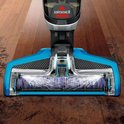 Blauw en grijs Bissell CrossWave vloerreinigingshoofd met roterende borstels op een houten vloer.