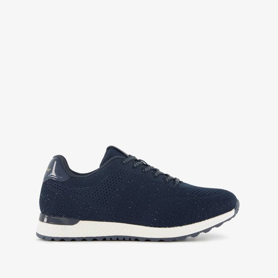 Zijkant van een donkerblauwe sneaker met gebreid bovenwerk, witte zool en glanzend hieldetail.