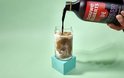 Douwe Egberts espresso concentrate, zoete chocolade smaak, wordt in een glas met ijs en melk gegoten.