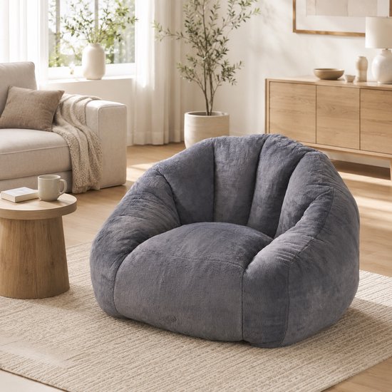 Grote, donkergrijze, pluizige zitzak op een beige tapijt in een modern wooninterieur.