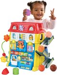 Meisje speelt met speelhuis met balglijbaan, rode dak en speelgoed.