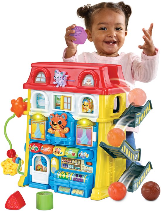 Meisje speelt met speelhuis met balglijbaan, rode dak en speelgoed.