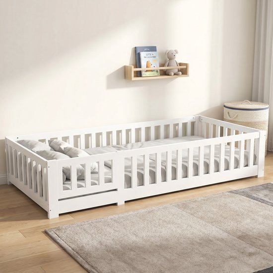 Wit Montessori bed met houten lattenbodem en grijze gestreepte kussens.
