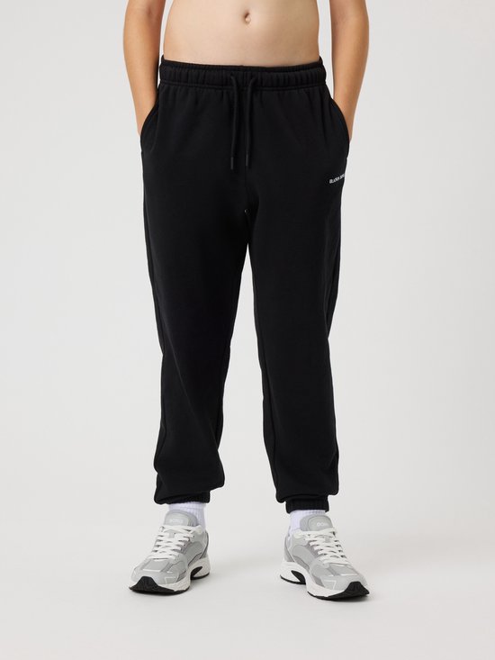 Voorkant van een jongen in zwarte joggingbroek met "Björn Borg" logo en grijze sneakers.