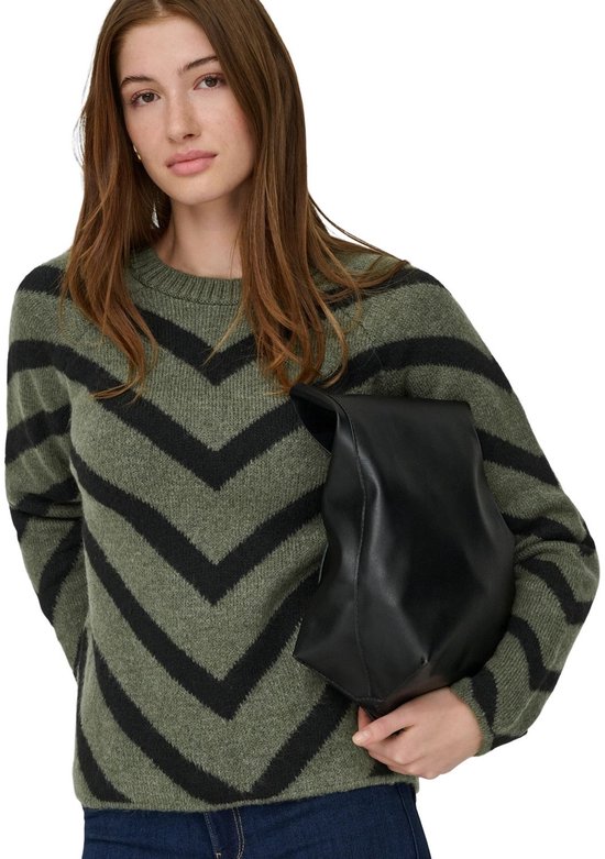 Model met olijfgroene trui met zwarte V-strepen en een zwarte tas.