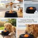 Hond likt aan oranje bal in zwarte bak met pindakaas, in de vriezer, en in de tuin.