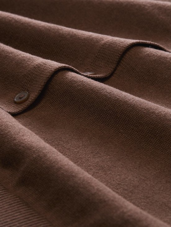 Detail van bruin gebreid vest met knopen en een gestreepte rand.