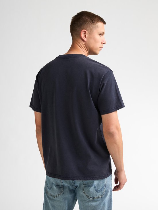 Zijaanzicht van model in donkerblauw T-shirt en jeans.