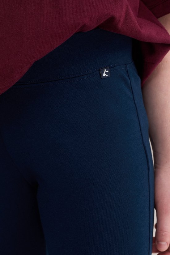 Close-up van donkerblauwe legging met een klein wit logo op de linkerheup.