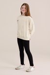 Meisje in crème kleurige sweater met sterrenprint en zwarte legging.