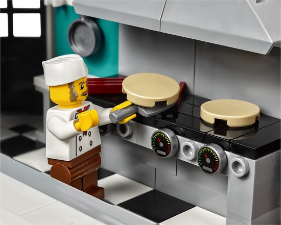 LEGO kok in witte chefkleding die pannenkoeken bakt op een fornuis.