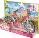 Roze Barbie fiets met lichtblauwe spatborden en velgen, rieten mandje met bloemen en helm.
