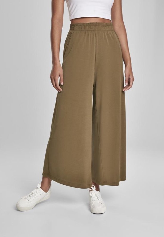 Model in olijfgroene wijde culotte met steekzakken en elastische tailleband.