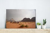 Canvas Schilderij Kamelen trek in de rode woestijn van Wadi Rum in Jordanië - 30x20 cm - Wanddecoratie