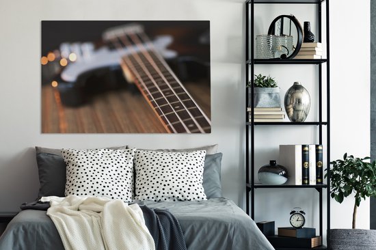 Une guitare basse repose sur une table Toile 140x90 cm - Tirage photo sur toile (Décoration murale salon / chambre)