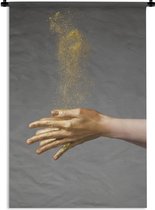Wandkleed Goud - Vrouw met goud geverfde handen en een wolk van glitters Wandkleed katoen 90x135 cm - Wandtapijt met foto