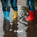 Blauwe, gele en rode rubberen laarzen voor kinderen in een waterplas. Denim broeken zichtbaar.