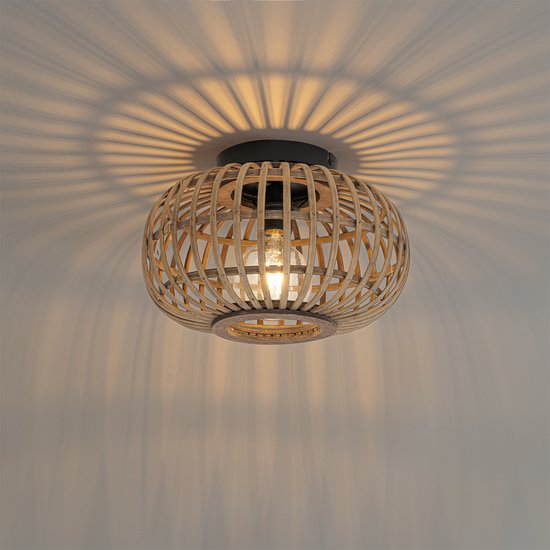 Oosterse plafondlamp aan het plafond, werpt decoratieve schaduwen door de rotan kooi.
