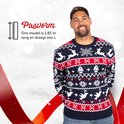 Man in kersttrui met rendieren, sneeuwvlokken en kerstbomen in blauw, rood en wit.