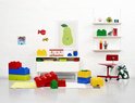 Kinderkamer met opgestapelde Lego opbergdozen (rood, geel, blauw, groen), een bureaulamp, een stoel en kunst aan de muur.